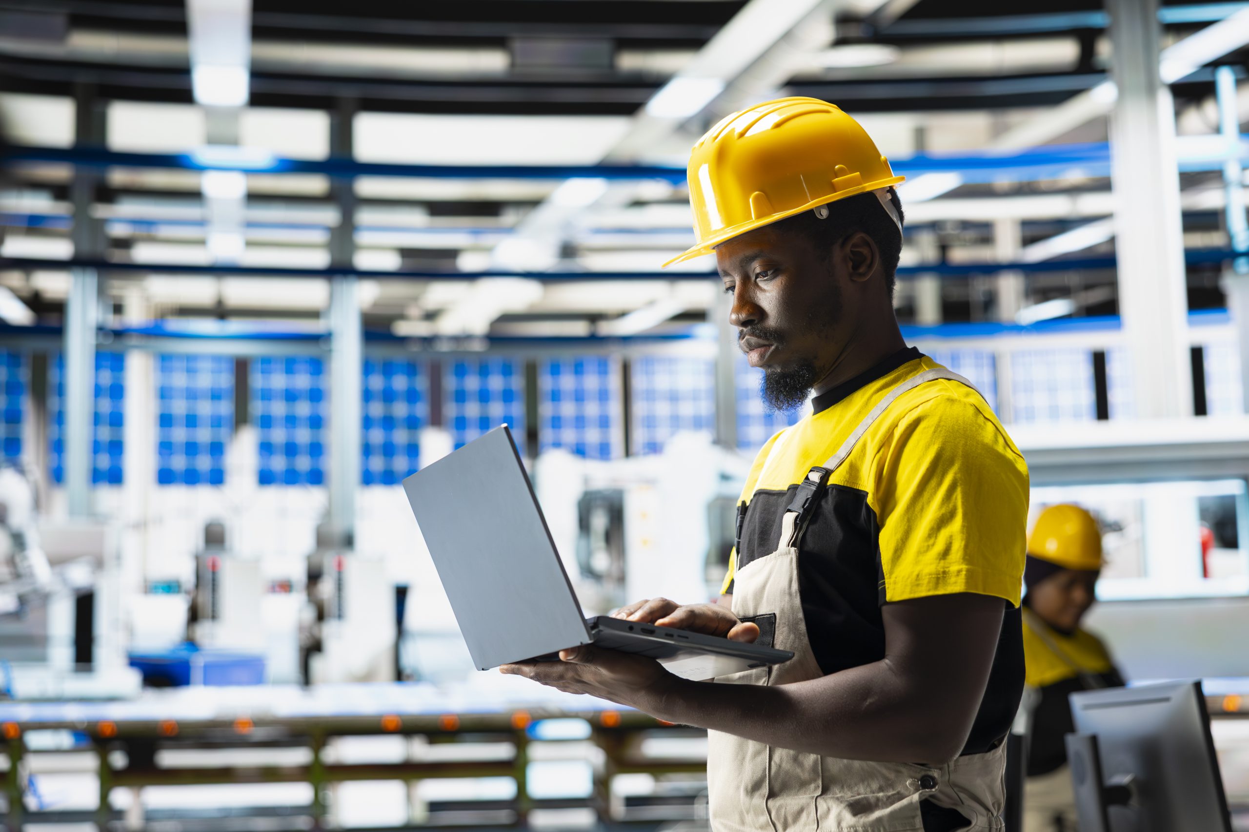 Photovoltaics factory engineer using laptop to do performance testing of solar panel production line. Technician improving sustainable solar energy configurations for cost reduction.
